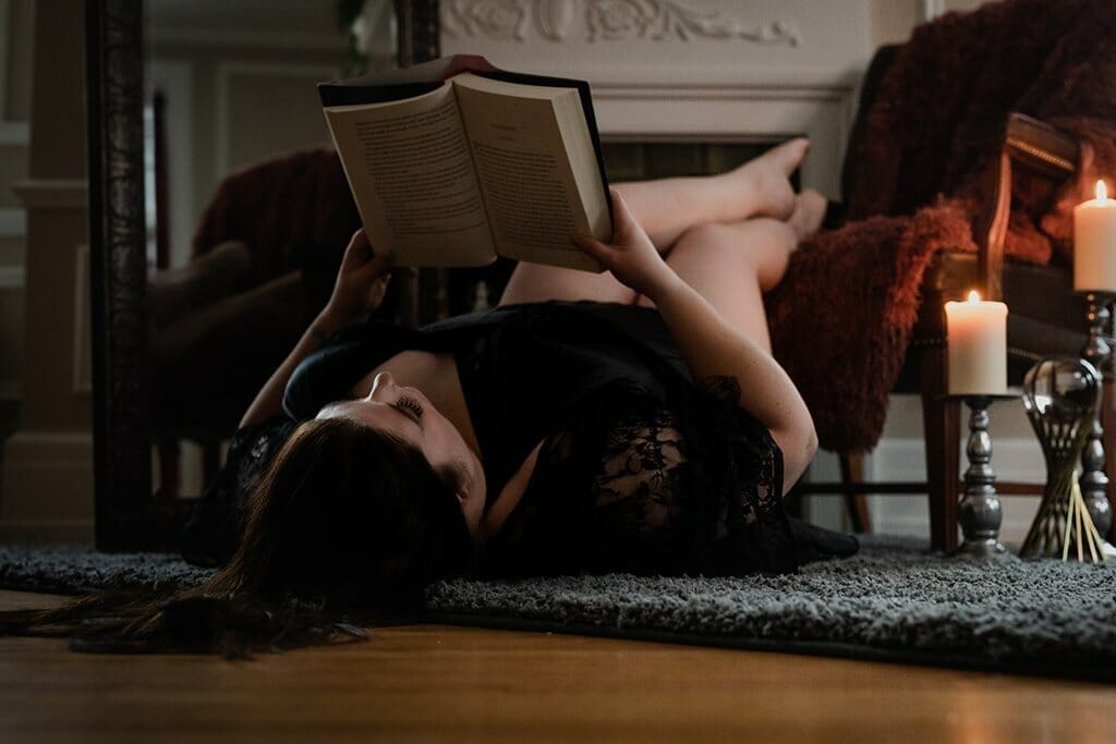 a women lying on the floor reading a book in lingerie who booked my boudoir session
