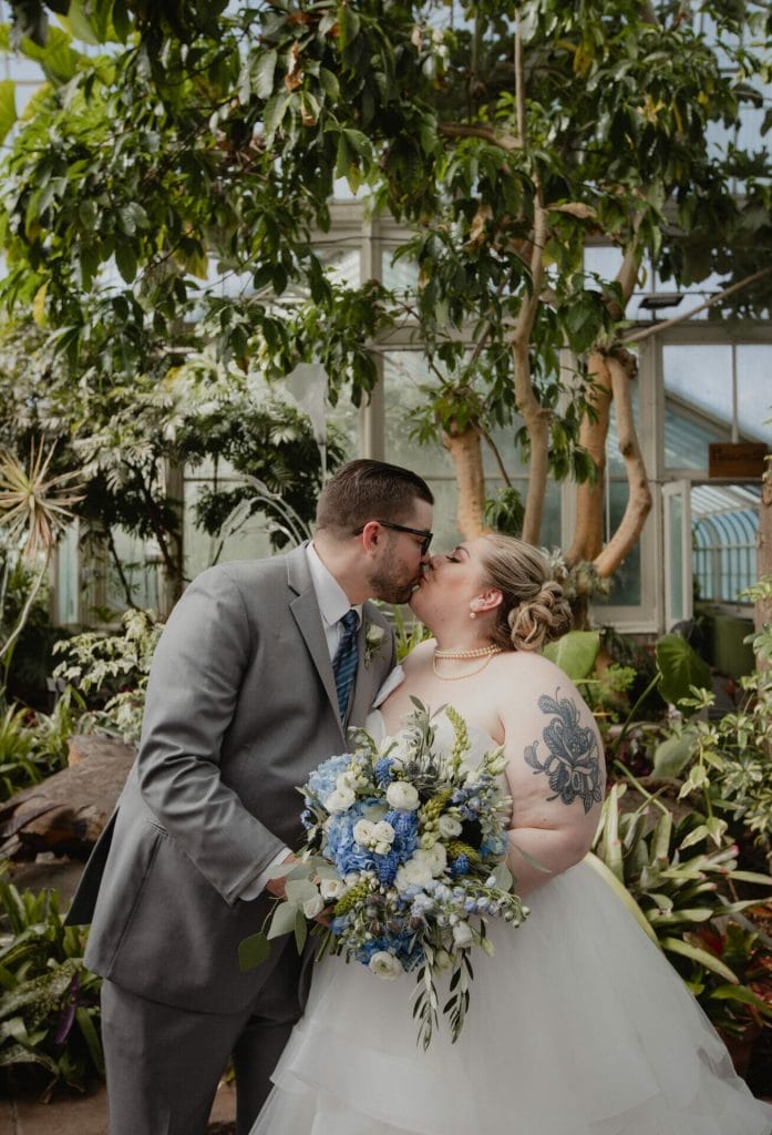 bride and groom kiss in indoor garden