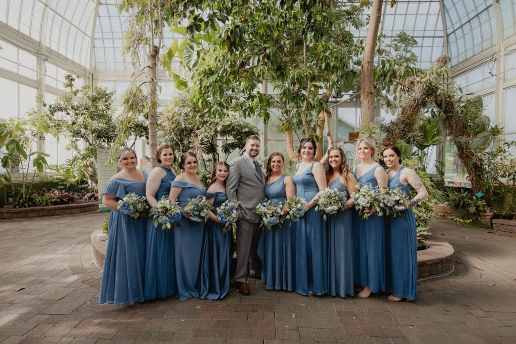 groom and bride's maids pose in botanical garden