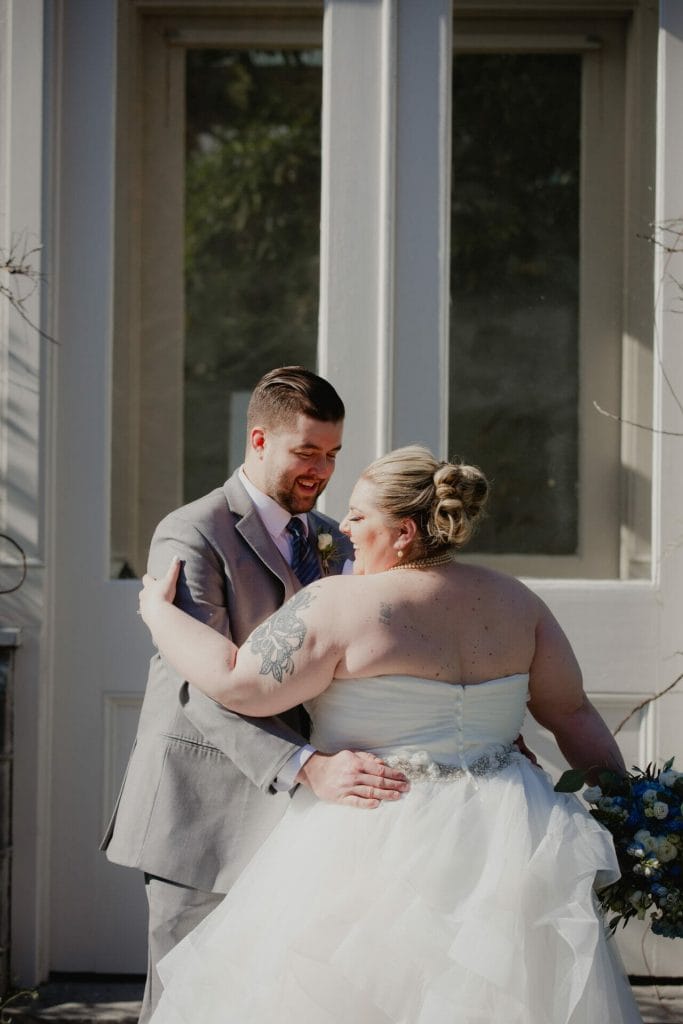 bride and groom embrace in front of botanical gardens