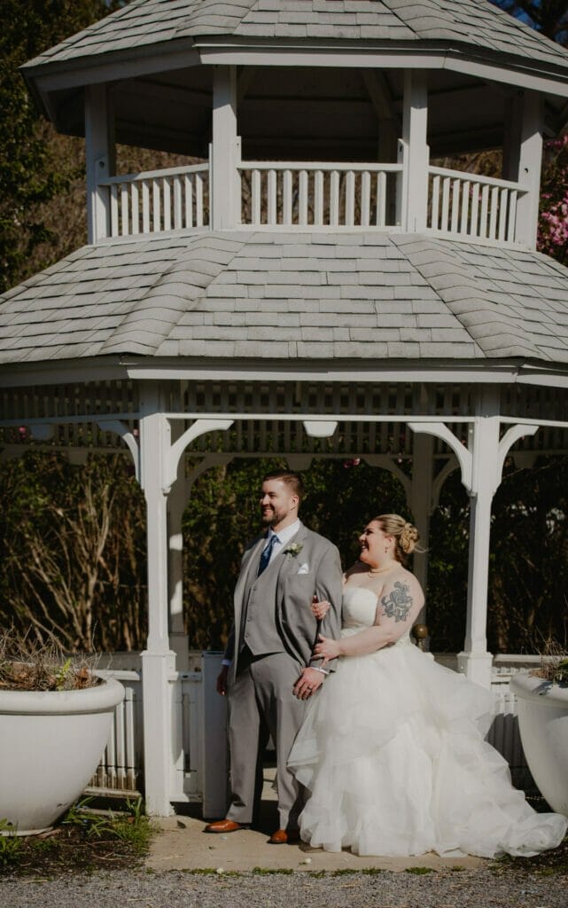 bride and groom pose in front of gazebo
