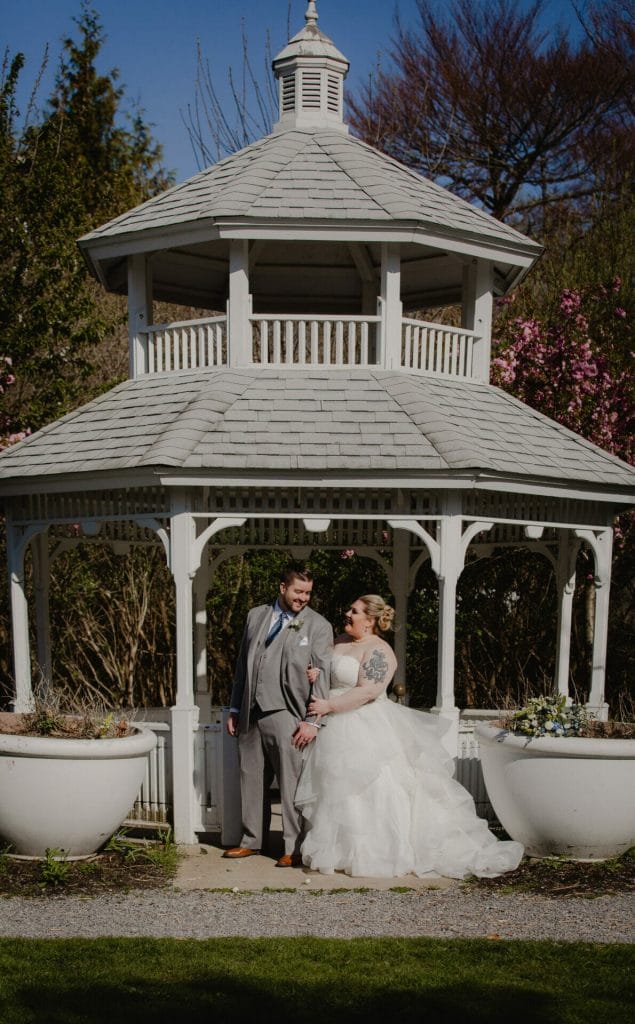 bride and groom stand in front of gazebo