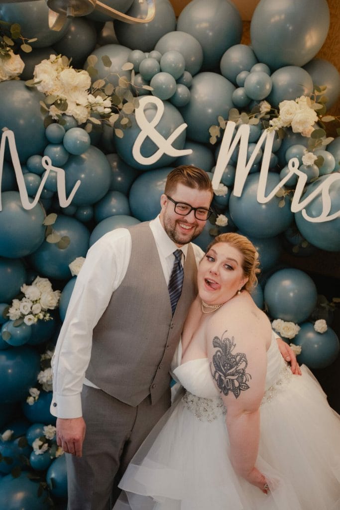 groom and bride pose in front of balloons